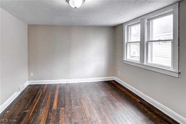 spare room with a wealth of natural light, dark hardwood / wood-style flooring, and a textured ceiling