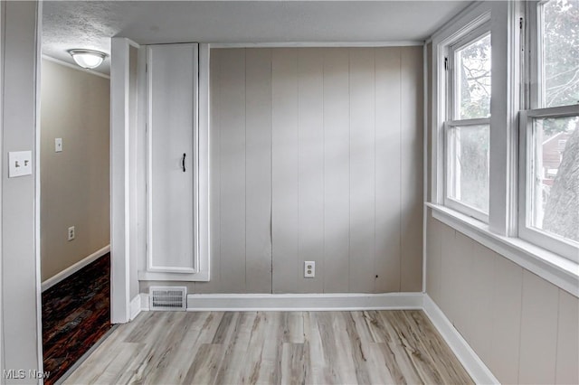 unfurnished room with a textured ceiling and light hardwood / wood-style floors