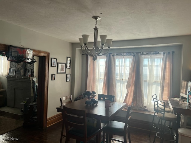 dining area featuring dark hardwood / wood-style floors, an inviting chandelier, and a textured ceiling