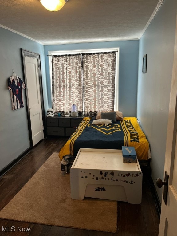 bedroom featuring a textured ceiling, dark wood-type flooring, and crown molding