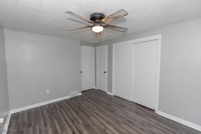 unfurnished bedroom with dark wood-type flooring, ceiling fan, and a closet