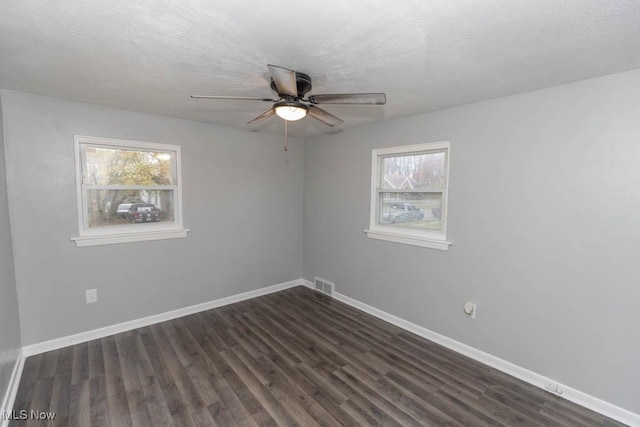 spare room with ceiling fan, a healthy amount of sunlight, dark hardwood / wood-style flooring, and a textured ceiling