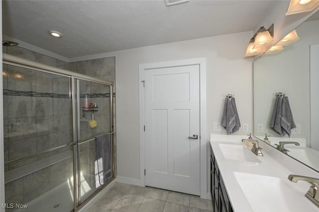 bathroom featuring a textured ceiling, walk in shower, tile patterned floors, and vanity