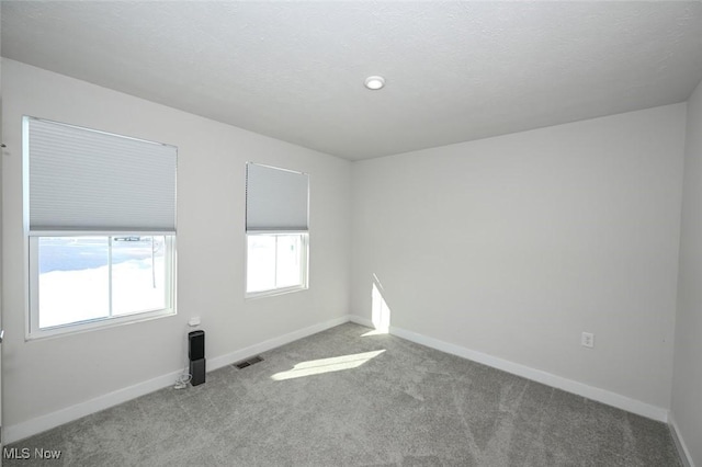 carpeted spare room featuring a textured ceiling