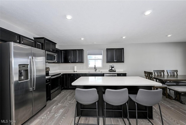 kitchen with light hardwood / wood-style flooring, appliances with stainless steel finishes, sink, and a center island