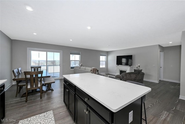 kitchen featuring a kitchen breakfast bar, a kitchen island, dishwasher, and dark hardwood / wood-style floors