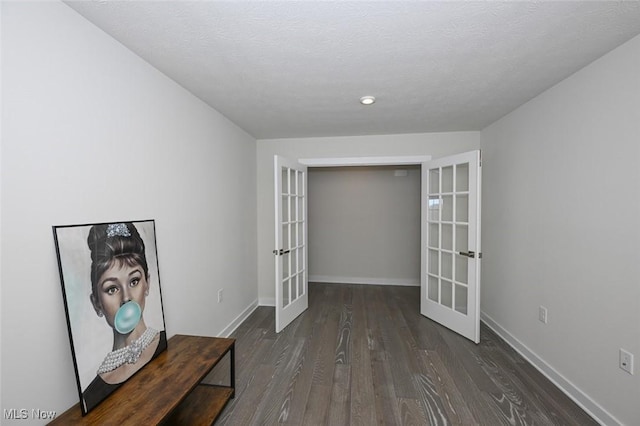 corridor with french doors, dark hardwood / wood-style floors, and a textured ceiling