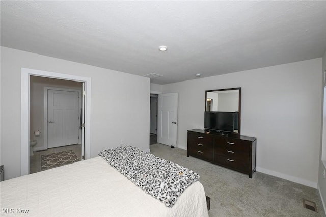 bedroom with light colored carpet and ensuite bath