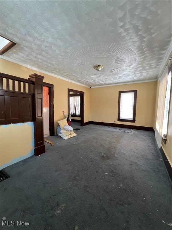 empty room with a skylight, a textured ceiling, and crown molding