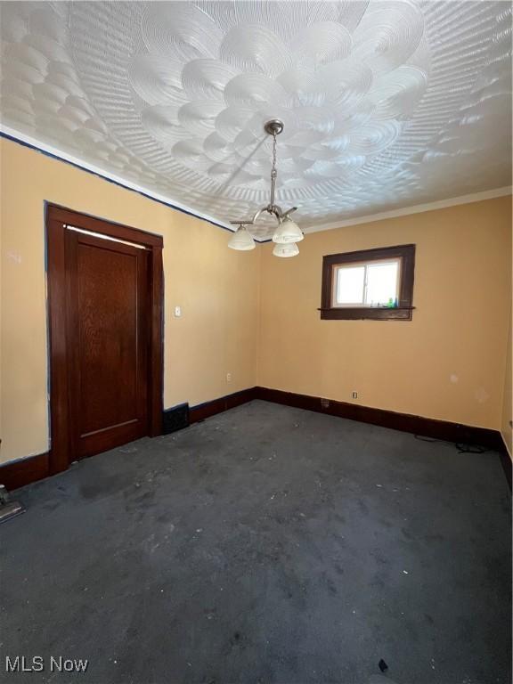 spare room featuring ornamental molding and concrete floors