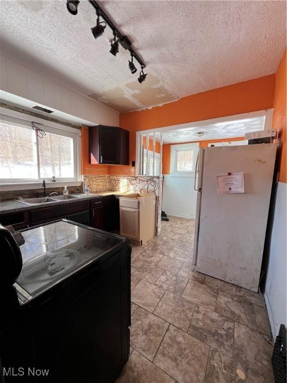 kitchen with fridge, sink, plenty of natural light, black range with electric cooktop, and track lighting