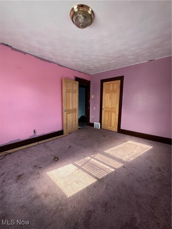 carpeted empty room with a textured ceiling