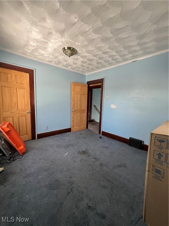 unfurnished bedroom with a textured ceiling, ornamental molding, and carpet flooring