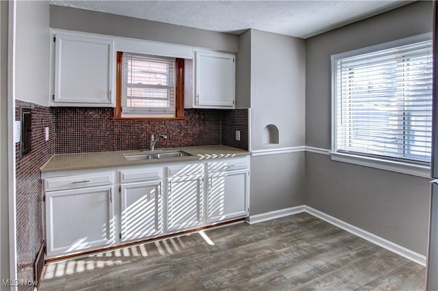 kitchen with wood-type flooring, sink, white cabinets, backsplash, and a textured ceiling