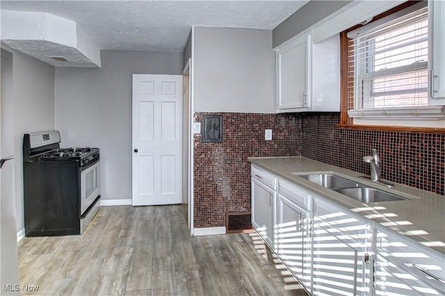 kitchen featuring sink, stainless steel gas range, a textured ceiling, white cabinets, and light wood-type flooring