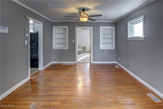 unfurnished room with crown molding, built in features, ceiling fan, and light hardwood / wood-style flooring