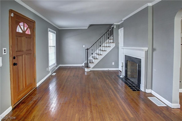 foyer featuring a tiled fireplace, crown molding, and dark wood-type flooring