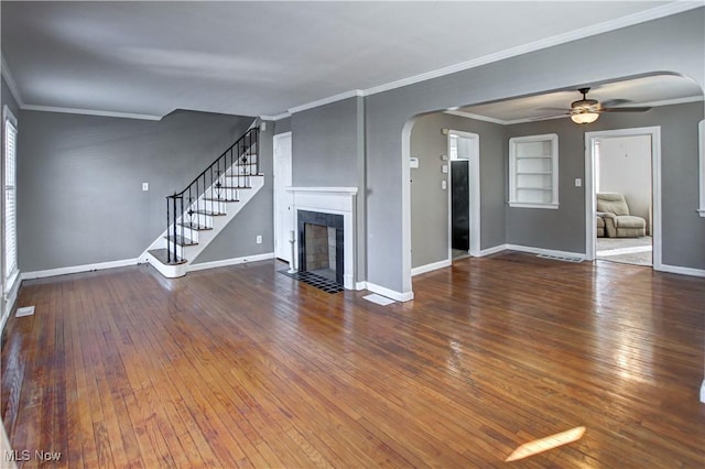 unfurnished living room with a tile fireplace, wood-type flooring, ceiling fan, and crown molding