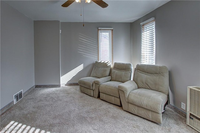 carpeted living room with heating unit and ceiling fan