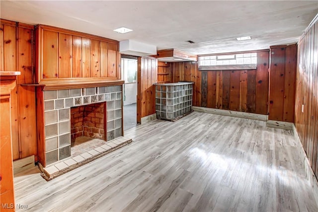 unfurnished living room featuring wooden walls and light hardwood / wood-style floors