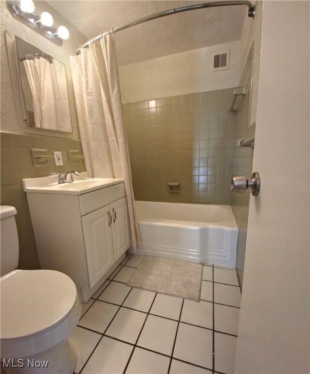 full bathroom with toilet, vanity, tile walls, tile patterned flooring, and shower / bath combo