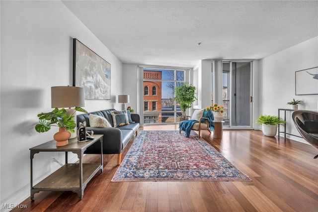 living room with a textured ceiling, floor to ceiling windows, and hardwood / wood-style floors