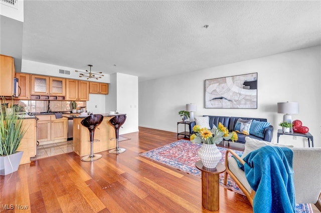 living room featuring ceiling fan, a textured ceiling, and light hardwood / wood-style flooring