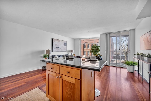 kitchen featuring a center island, a kitchen bar, expansive windows, a textured ceiling, and dark hardwood / wood-style flooring