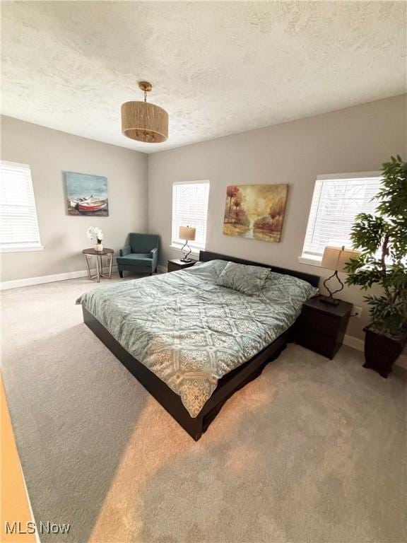 carpeted bedroom featuring multiple windows and a textured ceiling