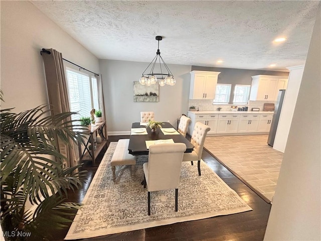 dining space with an inviting chandelier, light hardwood / wood-style floors, and a textured ceiling