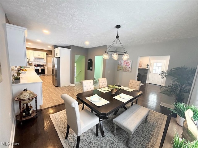 dining area featuring wood-type flooring and a textured ceiling