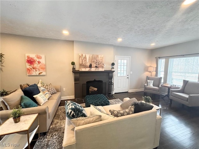 living room with a healthy amount of sunlight, dark wood-type flooring, and a textured ceiling