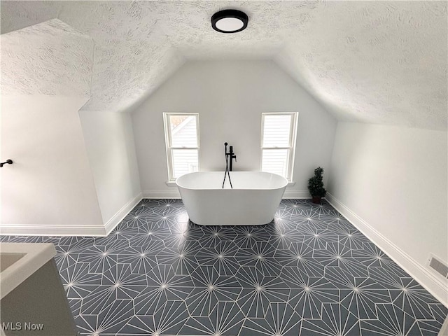 interior space featuring lofted ceiling, tile patterned floors, and a textured ceiling