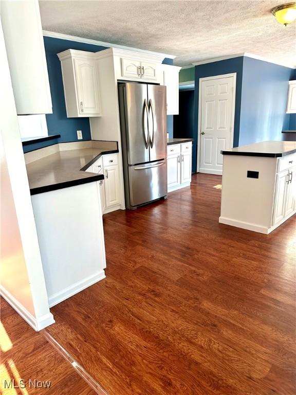 kitchen with white cabinetry, kitchen peninsula, and stainless steel refrigerator