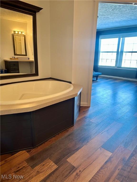 bathroom with wood-type flooring, tiled tub, and vanity