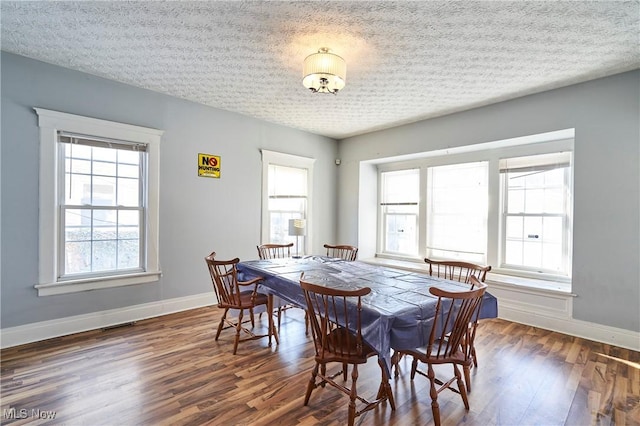 dining space featuring a textured ceiling and dark hardwood / wood-style flooring