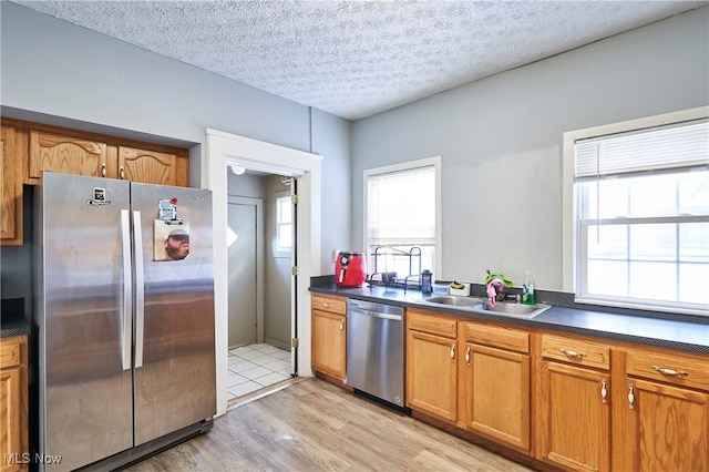 kitchen with a textured ceiling, appliances with stainless steel finishes, light wood-type flooring, and sink