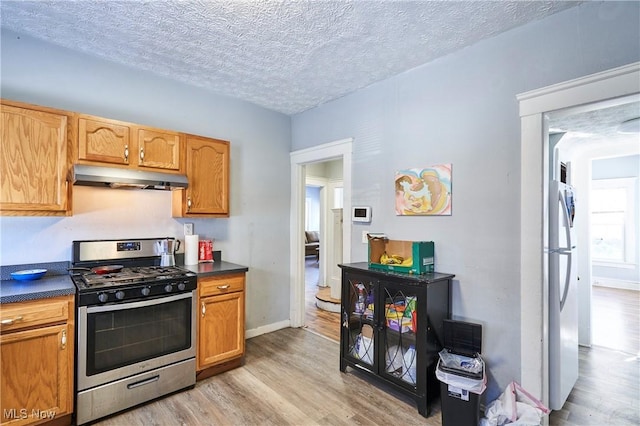 kitchen with stainless steel gas stove, fridge, a textured ceiling, and light wood-type flooring