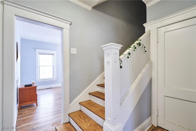 staircase with hardwood / wood-style flooring and crown molding