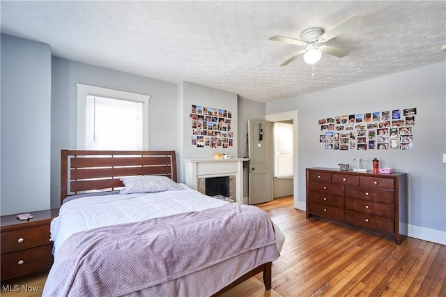 bedroom with a textured ceiling, ceiling fan, and light hardwood / wood-style flooring