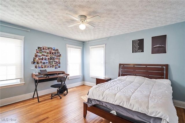 bedroom featuring ceiling fan, multiple windows, and wood-type flooring