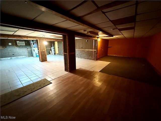 basement featuring brick wall and light hardwood / wood-style floors