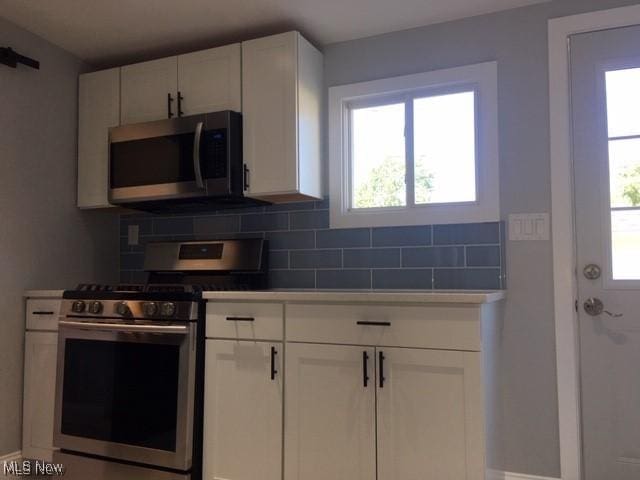 kitchen featuring white cabinets, stainless steel appliances, and tasteful backsplash