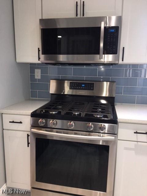 kitchen with tasteful backsplash, appliances with stainless steel finishes, and white cabinetry