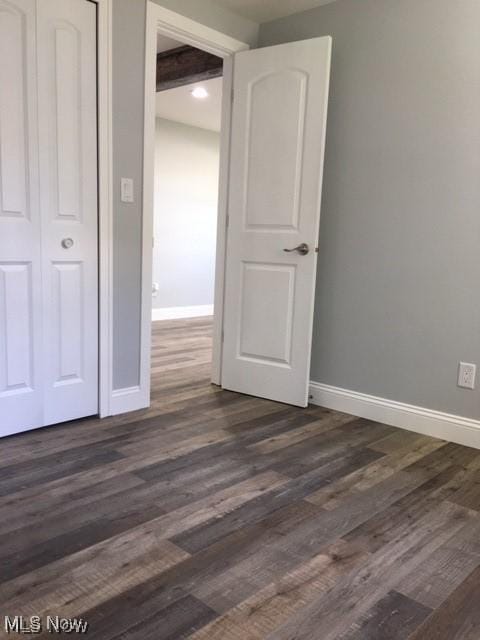 unfurnished bedroom with dark wood-type flooring and a closet