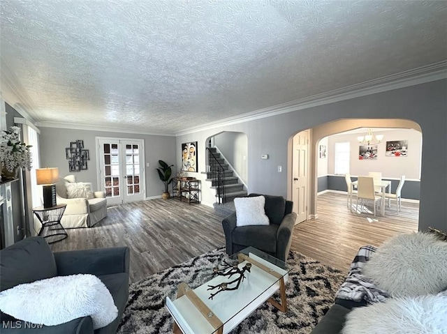 living room with french doors, crown molding, a textured ceiling, and wood-type flooring