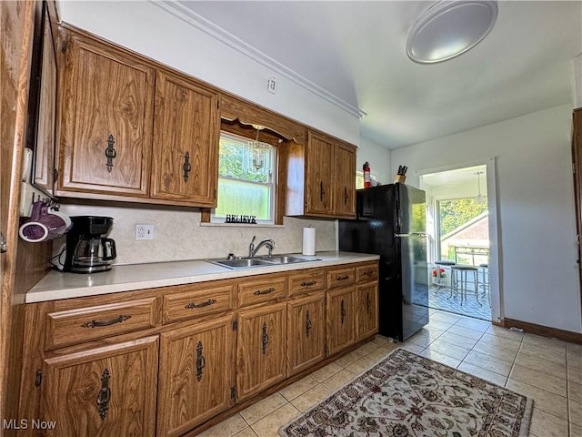 kitchen with black fridge, light tile patterned floors, decorative backsplash, and sink