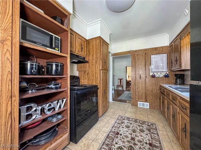 kitchen featuring wooden walls, light tile patterned floors, crown molding, and black range with electric stovetop