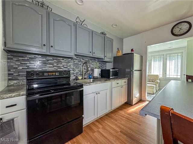 kitchen with gray cabinets, appliances with stainless steel finishes, backsplash, light hardwood / wood-style flooring, and sink