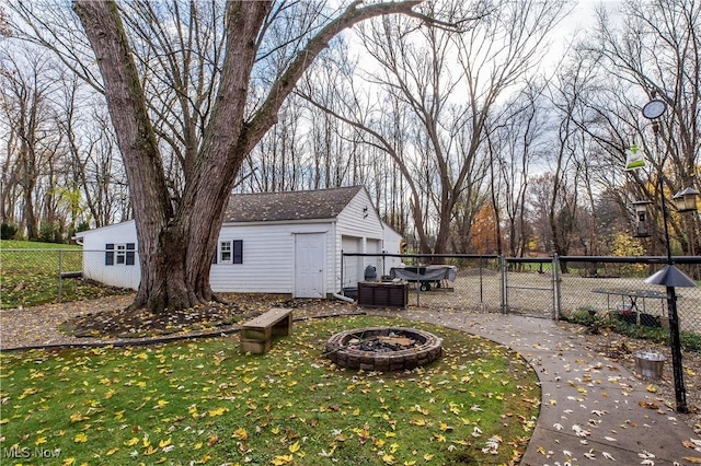 view of yard with a garage, an outdoor fire pit, and an outdoor structure